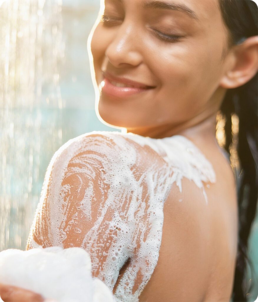 Smiling woman washing her shoulder with foam