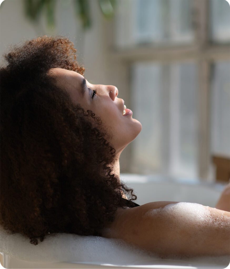 Woman relaxing in a bubble bath with her head tilted back